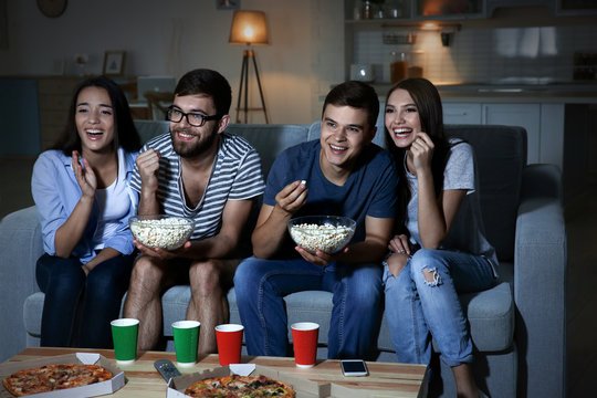 Friends together on a couch watching a movie